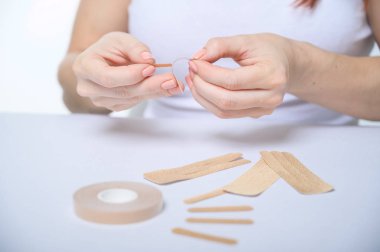 Kadın eli, yaşlanmaya karşı yüzlerine bir yama yapıştırır. Yüz gerdirme için bant. Tanımlanamayan kadın Kinezio kasetleriyle gençleşmiş.