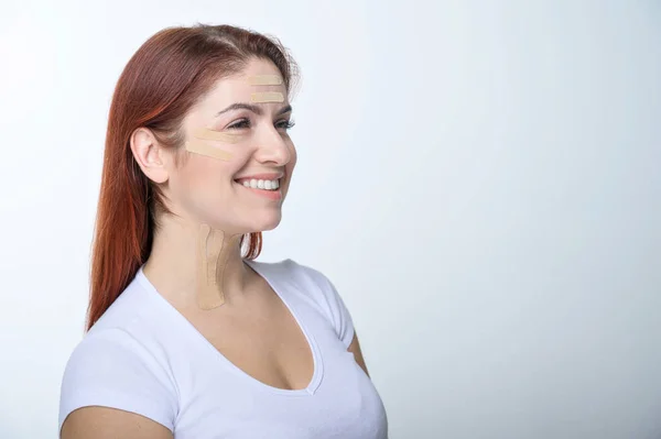 Retrato de uma mulher ruiva com fitas na face de cor da pele para rejuvenescimento. Uma maneira alternativa de combater as rugas . — Fotografia de Stock