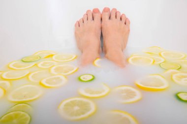 Kız limon ve limonla süt banyosu yapıyor. Citrus spa 'sı. Vücut bakımı. Cilt beyazlatıcı. Kadın ayağı..