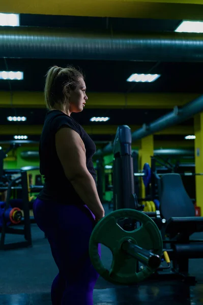Kövér európai nő foglalkozik fitness egy súlyzóval a tornateremben. Egy kövér lány halálos emelést csinál.. — Stock Fotó