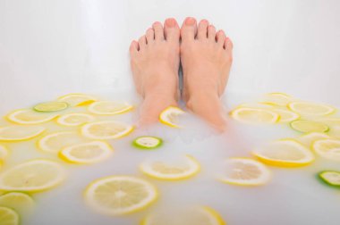 Kız limon ve limonla süt banyosu yapıyor. Citrus spa 'sı. Vücut bakımı. Cilt beyazlatıcı. Kadın ayağı..