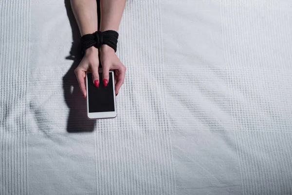 Primer plano de las manos atadas hembra sosteniendo un teléfono inteligente. Dependiendo del teléfono móvil y gadgets . — Foto de Stock