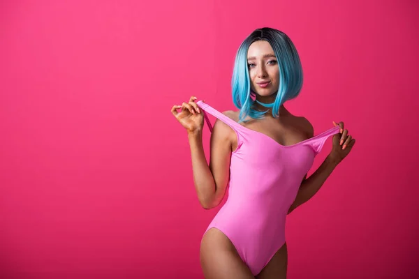 Vacker kvinna i rosa monokini och blå peruk i studion. Flicka med artificiellt kort hår poserar i en färgad baddräkt. — Stockfoto