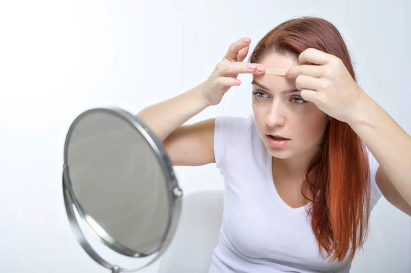 Une femme met une cassette de cinézio sur son front. portrait d'une fille fait des applications sur son visage contre les rides du visage. Une alternative au botox et à l'acide hyaluronique à la maison . — Photo