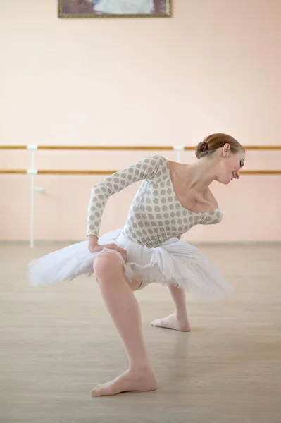 Uma bailarina muito flexível em um tutu fica em um plie em uma classe com máquinas de balé. Hipermobilidade das articulações e displasia do tecido conjuntivo . — Fotografia de Stock