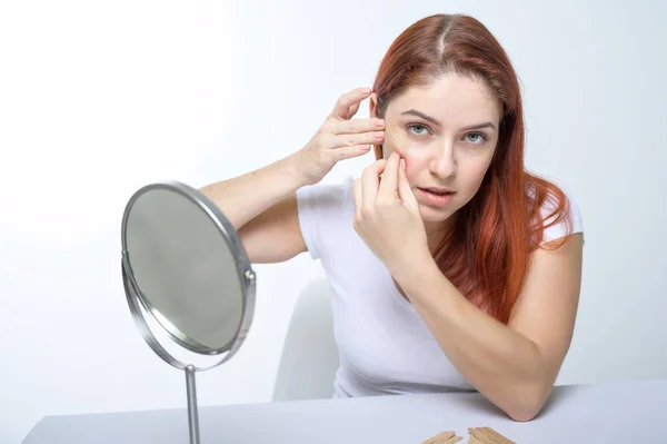 A woman sticks a kinezio tape on her forehead. portrait of a girl makes applications on her face against facial wrinkles. An alternative to botox and hyaluronic acid at home.