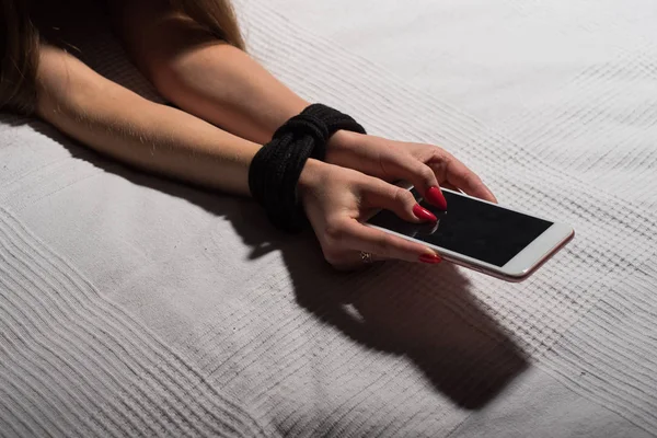 Primer plano de las manos atadas hembra sosteniendo un teléfono inteligente. Dependiendo del teléfono móvil y gadgets . —  Fotos de Stock