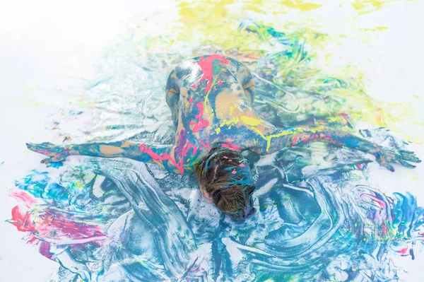 Vista superior de uma mulher nua em um spray de tinta. Uma menina sem roupas está em um piso branco em pontos coloridos. Pintura corporal original . — Fotografia de Stock