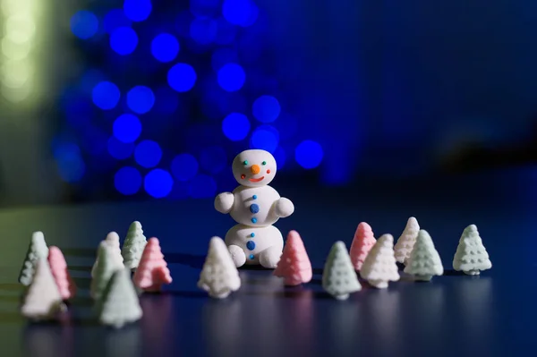 Bonhomme de neige mignon et petits arbres de Noël faits de guimauves sur le fond des lumières de Noël. Guirlande d'ampoules sur un arbre. Bonne année. — Photo