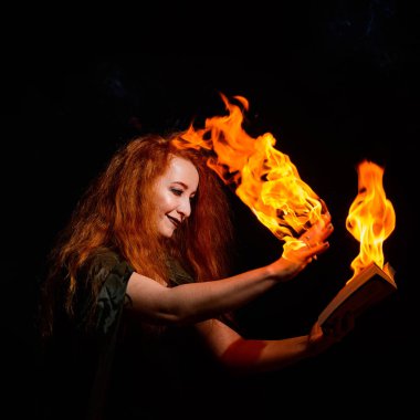 Uğursuz bir cadı büyü kitabını düşüncenin gücüyle ateşe veriyor. Kızıl saçlı kadın cadılar bayramı için sihirbazlık yapıyor. Ellerinde alevler.