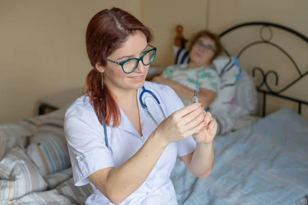 Rufen Sie zu Hause einen Arzt an. Die Krankenschwester gibt einer älteren Patientin eine intramuskuläre Injektion. Rentner ist krank und liegt im Bett. — Stockfoto