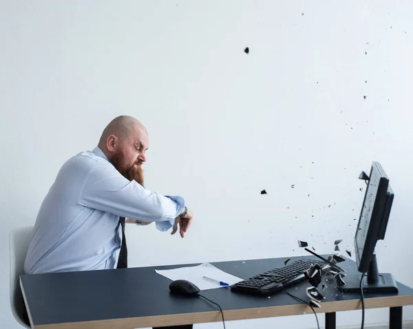 Un hombre barbudo está teniendo una crisis nerviosa en el trabajo. El gerente de la oficina se asusta y rompe una taza en el monitor . —  Fotos de Stock