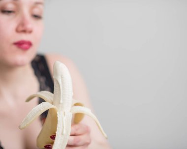 Siyah dantelli iç çamaşırlı bir sarışın baştan çıkarıcı bir şekilde muz yalıyor. Şehvetli kırmızılı kadın oral zevki taklit eder..