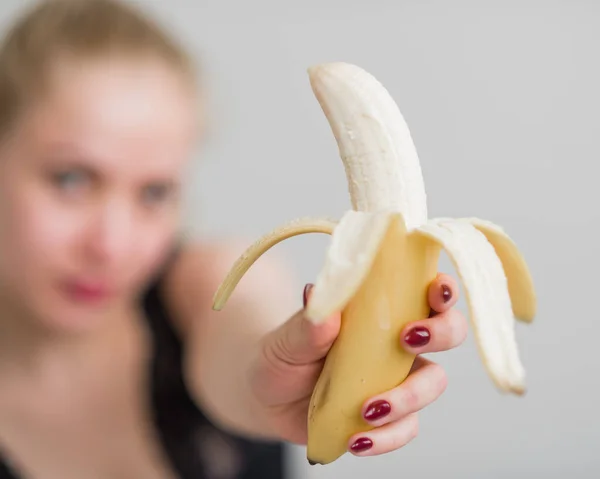 Une blonde en lingerie dentelle noire suce et lèche une banane de façon séduisante. Femme au rouge sensuel imite le plaisir oral . — Photo