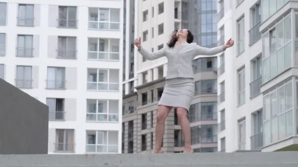 Exitosa mujer de negocios bailando y saltando de alegría en la calle. Hermosa chica en un traje de negocios se regocija en las escaleras. Movimiento lento . — Vídeos de Stock