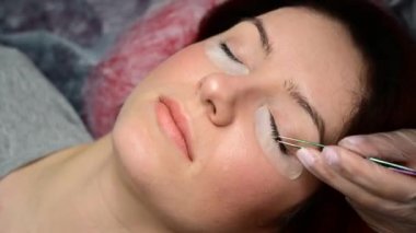 Hızlandırılmış video. Kirpik uzatma işlemini cımbızla hızlandırın. Usta müşteriye yapay kirpikler yapıştırıyor..