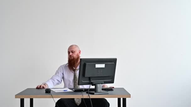Angry bald man with a red beard in the office in a business suit smashes an ax with a computer. The manager with a nervous breakdown, breaks the monitor. — Stock Video