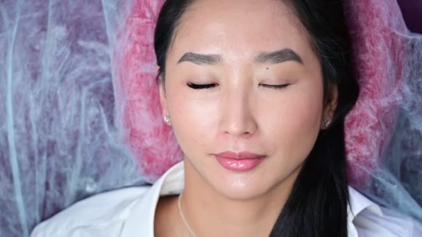 Porträt einer schönen asiatischen Frau öffnet ihre Augen während der Wimpernverlängerung. Doppeltes Wimpernvolumen vor und nach. — Stockvideo