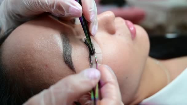 Närbild av en vacker asiatisk kvinna på ögonfransförlängning förfarande. Dubbel volym lösögonfransar. Lashmaker på jobbet. — Stockvideo