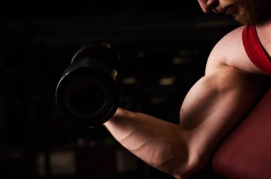 Spor salonunda pazı egzersizi yapan tanınmamış bir adam. Kaslı adam vücut geliştirmekle meşgul. Erkek ellerine yakın çekim.