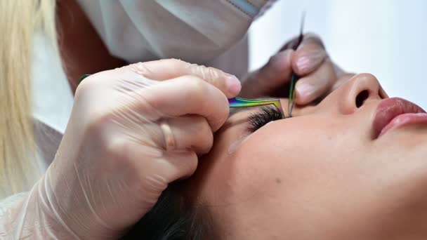 Close-up de uma bela mulher asiática no procedimento de extensão de pestanas. Cílios falsos de volume duplo. Lashmaker no trabalho. — Vídeo de Stock