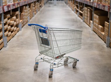 Mobilya deposunda boş bir alışveriş arabası. Kutu rafı soyut bulanık arka planla süpermarket alışveriş sepeti koridoru