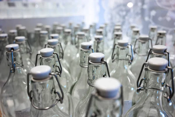 Un primo piano del collo di una bottiglia. Gruppo di bottiglie vuote con tappi di plastica in un negozio sul bancone . — Foto Stock