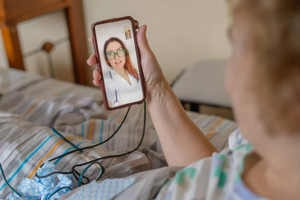 An elderly woman talking to the doctor on the phone. A pensioner suffers from a respiratory illness and makes a video call to the therapist. Online consultation — 스톡 사진