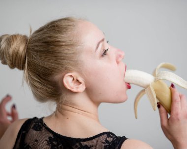 Siyah dantelli iç çamaşırlı bir sarışın baştan çıkarıcı bir şekilde muz yalıyor. Şehvetli kırmızılı kadın oral zevki taklit eder..