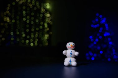 Tatlı kardan adam ve Noel ışıklarının arka planında marşmelovdan yapılmış küçük Noel ağaçları. Beyaz fincan sıcak çikolata ve tatlı..