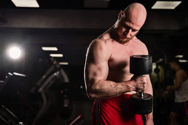 Hezký muž bez košile, cvičí bicepsy a tricepsy s činkou. Vyražený kulturista s krásným tělem. Svalový trenér v tělocvičně. — Stock fotografie