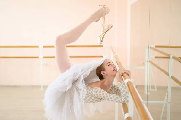 Bella ballerina si allena in una classe di danza. Giovane ballerina flessibile posa in scarpe da punta. Una donna in un corpo e un tutù bianco balla una danza classica. — Foto Stock
