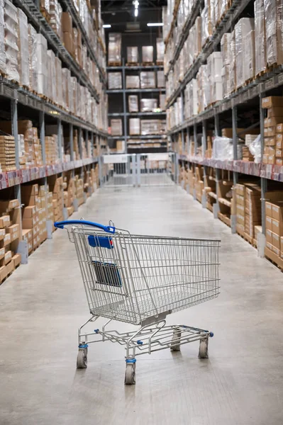 Mobilya deposunda boş bir alışveriş arabası. Kutu rafı soyut bulanık arka planla süpermarket alışveriş sepeti koridoru