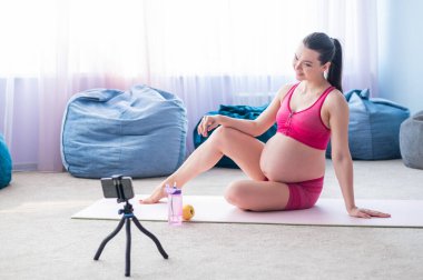 Hamile kadınlar için online dersler. Avrupalı bir kadın telefonda video fitness dersi veriyor. Bir mucize bekliyorum. Bekleyen anneler için yoga..
