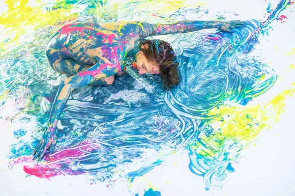 Vista superior de uma mulher nua em um spray de tinta. Uma menina sem roupas está em um piso branco em pontos coloridos. Pintura corporal original . — Fotografia de Stock