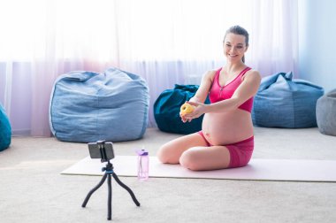 Hamile kadınlar için online dersler. Avrupalı bir kadın telefonda video fitness dersi veriyor. Bir mucize bekliyorum. Bekleyen anneler için yoga..