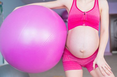 Yoga sınıfındaki tanınmayan hamile bir kadının görüntüsü. Müstakbel yüzü olmayan çıplak bir anne bir topla fitness yapıyor..