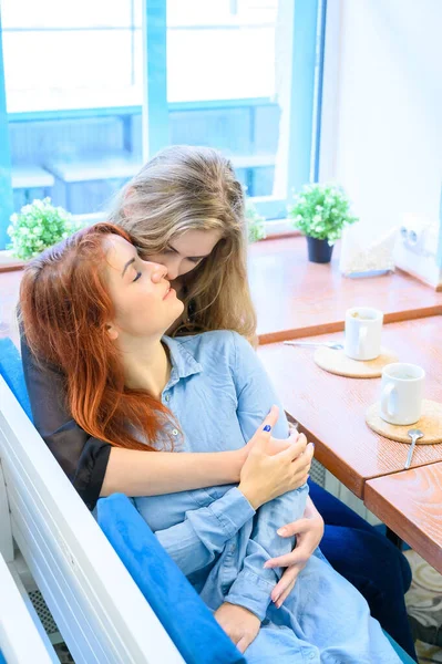 Zwei lesbische Frauen umarmen sich, während sie in einem Café sitzen. Gleichgeschlechtliche Beziehungen. Die Nähe und Zärtlichkeit zweier Mädchen. Homosexualität — Stockfoto