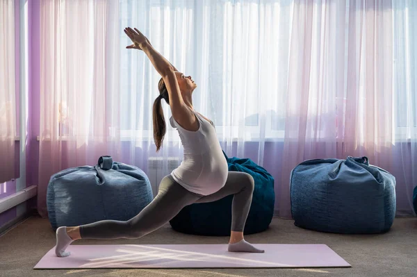 Pregnant woman practice yoga. A girl in the third trimester leads Pilates. Classes to prepare for childbirth. Waiting for the baby. Warrior Pose. — Stock Photo, Image