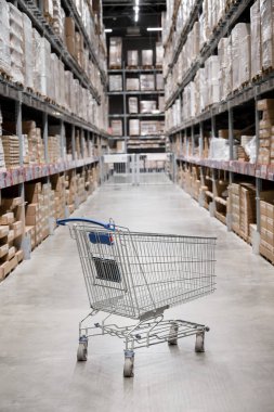 Mobilya deposunda boş bir alışveriş arabası. Kutu rafı soyut bulanık arka planla süpermarket alışveriş sepeti koridoru