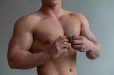 Erkek gövdesine yakın çekim. Tanınmayan tişörtsüz vücut geliştiren adam kendine testosteron enjekte ediyor. Yüzü olmayan sporcu uyuşturucu kullanıyor..