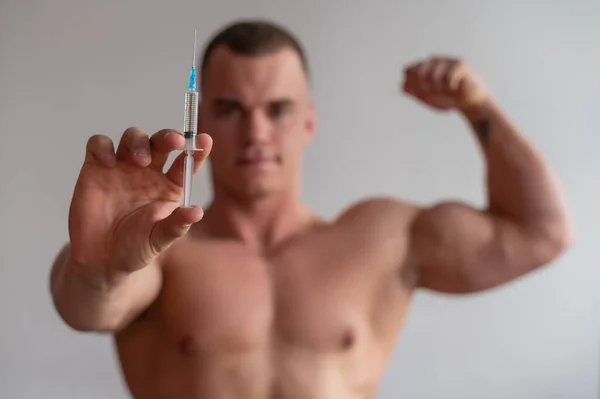 Culturiste masculin attrayant avec un torse nu tient une seringue de drogue. L'athlète se met une injection d'hormone de croissance . — Photo