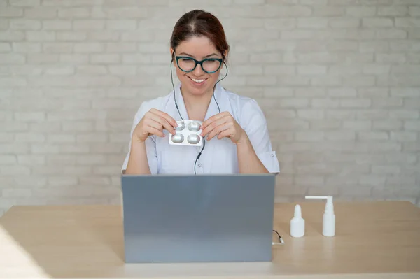 El médico lleva a cabo una consulta en línea en un ordenador portátil. Recepción remota al terapeuta en cuarentena. Médico mujer habla de drogas en el aire . —  Fotos de Stock