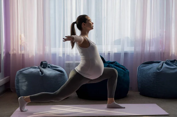 Pregnant woman practice yoga. A girl in the third trimester leads Pilates. Classes to prepare for childbirth. Waiting for the baby. Warrior Pose. — Stock Photo, Image
