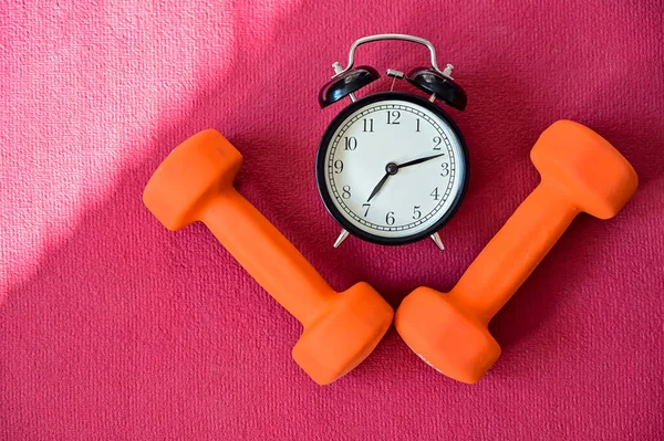 Два помаранчевих тунелі і будильник на рожевому килимку йоги. Час займатися самоізоляцією. Спорт з обладнанням вдома . — стокове фото