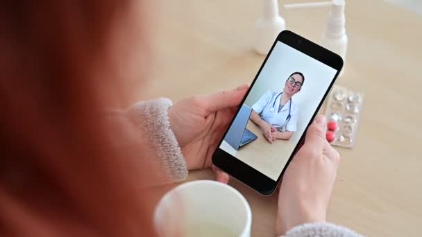 Felismerhetetlen nő online konzultáción egy orvossal a mobilján. A lány beteg, és beszél a kezelőorvos egy videohívást otthonról. A képernyő közelsége. — Stock videók