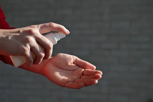 Las manos femeninas aplican aerosol antibacteriano con alcohol para prevenir la propagación de gérmenes, bacterias y virus. Concepto de higiene personal durante el período de la epidemia de enfermedades respiratorias . — Foto de Stock