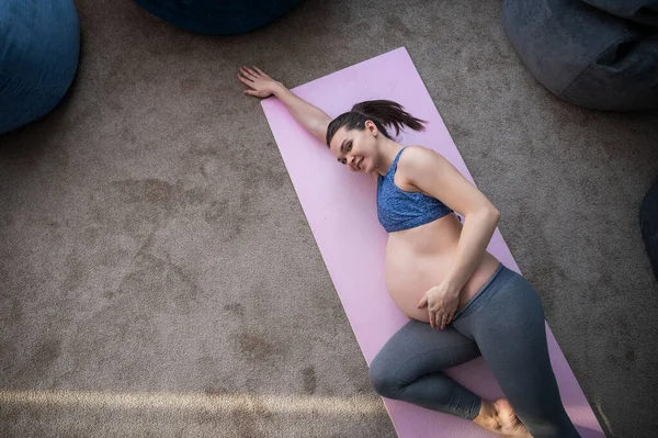 Těhotná Evropanka dělá pilates sama. Očekávaná matka v posledním trimestru cvičí jógu. Dívka se protáhla na 9 měsíců.. — Stock fotografie