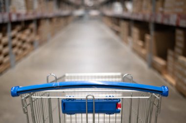 Mobilya deposunda boş bir alışveriş arabası. Kutu rafı soyut bulanık arka planla süpermarket alışveriş sepeti koridoru
