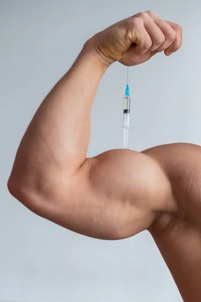 Großaufnahme des männlichen Bizeps. Ein unkenntlich gemachter männlicher Bodybuilder spritzt sich Testosteron. Gesichtsloser Sportler nimmt Wachstumshormon. Vertikal . — Stockfoto